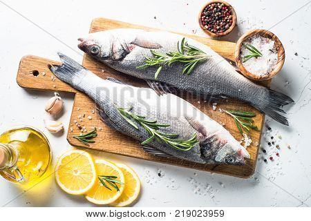 Fresh fish seabass. Raw fish seabass with spices and herbs ingredients for cooking on white background. Top view.