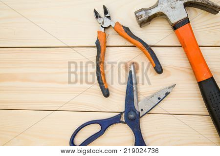 Renovating a house. A set of bright repair tools -pilers, scissors and a hammer on a light uncolored wooden background, close up. Top view. Space for your text or pruduct display.