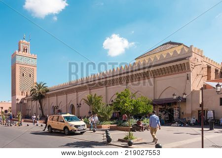 Marrakech Morocco. 12th May 2017: Shop owners and a taxi are waiting for customers while people are walking past the Moulay El Yazid Mosque in Marrakech Morocco on a sunny morning in May 2017.