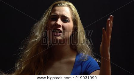 Beautiful Sexy Blonde Girl in Blue Dress is Singing and Dancing in Studio with Black Background.  
