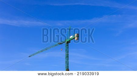 Tower construction crane ready for lifting. Blue sky backdrop. Space for text.