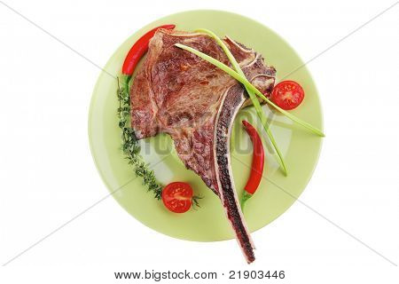 cibo di carne: arrosto nervatura sul piatto verde con timo pepe e pomodoro isolato su sfondo bianco