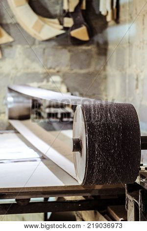 Industrial professional stationary abrasive sanding machine with long grinding belt. Mechanized woodworking carpenter tool in carpentry workshop. Limited depth of field.