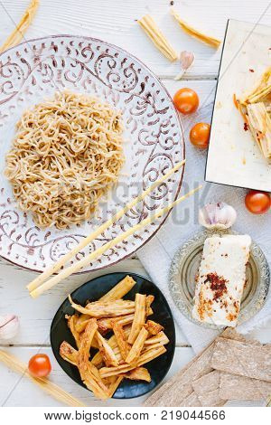 Top view of asian table with chinese noodles, roasted paneer or tofu and vegetables