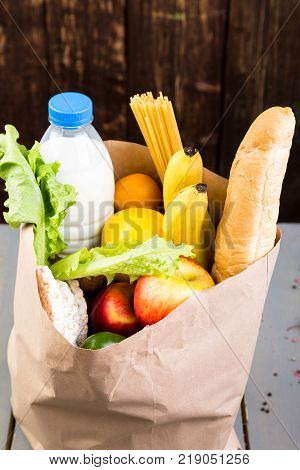 Grocery Shopping Concept. Different Food In Paper Bag On Wooden Background.  Flat Lay.