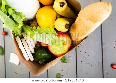 Grocery Shopping Concept. Different Food In Paper Bag On Wooden Background.  Flat Lay.