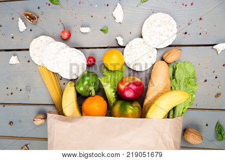 Grocery Shopping Concept. Different Food In Paper Bag On Wooden Background.  Flat Lay.