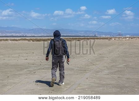Single man walking on dry salt lake in Limassol Cyprus. Alone and walking in desert conditions.