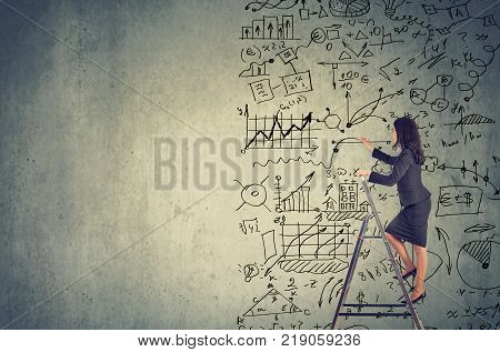 Businesswoman standing on ladder and drawing business plan ideas