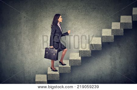 Businesswoman with briefcase stepping up a stairway career ladder