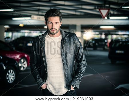 Handsome muscular man in casual clothing on background of parking.