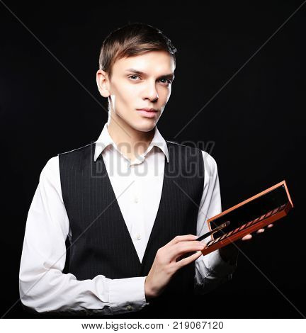 Male make-up artist  staying on dark  background, holding profes