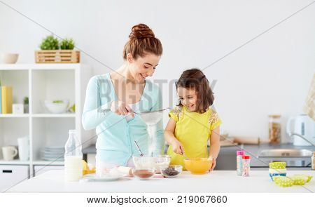 family, cooking, baking and people concept - happy mother and little daughter with sieve sifting flour and making dough at home kitchen