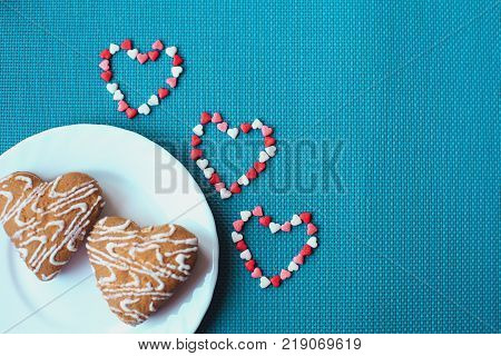 Cookies in the shape of heart on a small white plate on a blue background