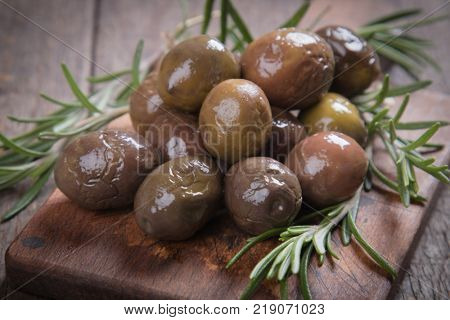 Cured, pickled or brined olive fruit on wooden table