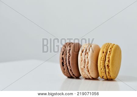 some delicious macarons of different flavors on a white table, against a white background wiht a blank space on top