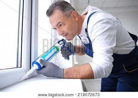 Construction worker installing window in house
