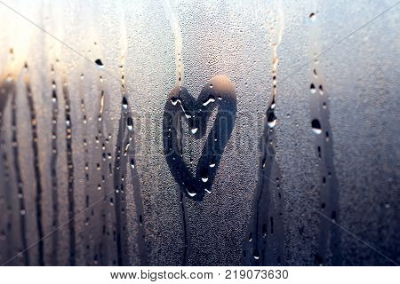 A rainy winter day seen through a wet window a moment before sunset.