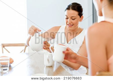 Young woman with her friend having tea at home