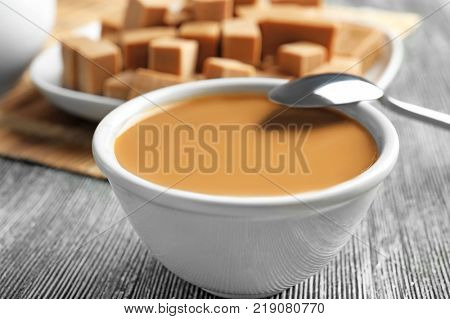 Bowl with sweet caramel sauce on table