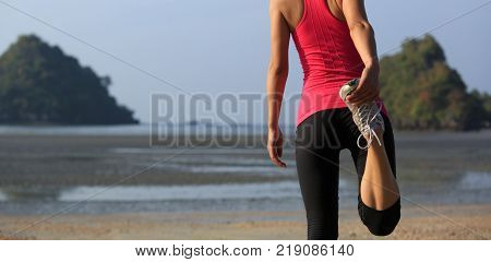 Young fitness woman warming up on sandy beach