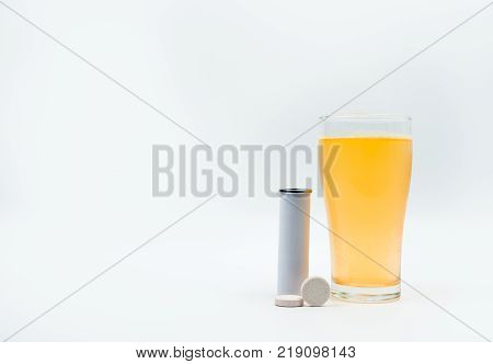 Effervescent tablets tube with blank label and orange effervescent bubbles of calcium and vitamin C in transparent glass. Vitamins minerals and supplement concept.
