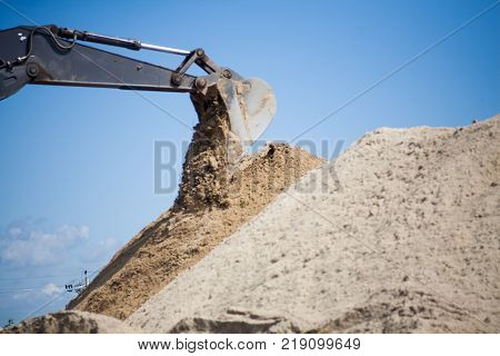 A large construction excavator of yellow color on the construction site in a quarry for quarrying