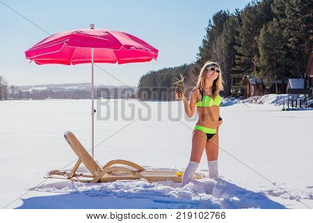 Novokuznetsk, Kemerovo region, Russia - 23 Feb, 2017 : White beaches of Siberia is an enterteiment activity where people playing beach games dressed in bikini in winter. Woman in bikini with pineapple
