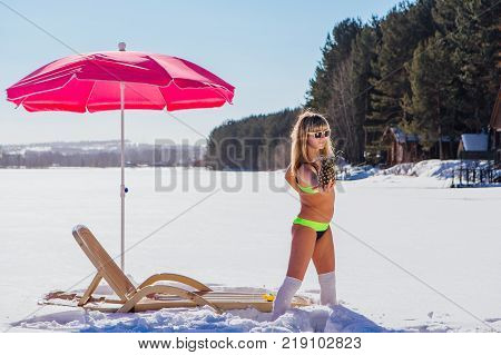 Novokuznetsk, Kemerovo region, Russia - 23 Feb, 2017 : White beaches of Siberia is an enterteiment activity where people playing beach games dressed in bikini in winter. Woman in bikini with pineapple