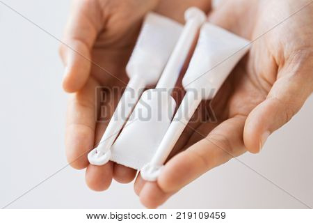 medicine, healthcare and pharmaceutics concept - hands holding tubes of micro enema