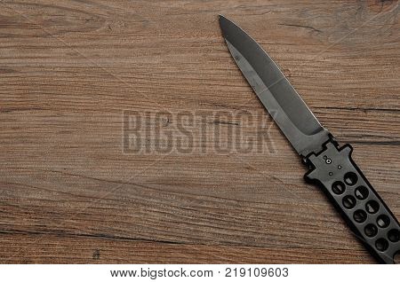 Steel butterfly knife (balisong) isolated on a wooden background