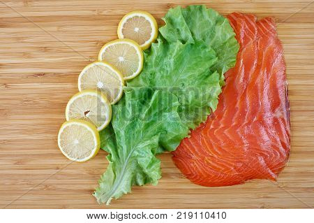 Smoked Fillet salmon with lemon and salad on a board