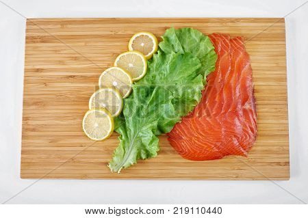 Smoked Fillet salmon with lemon and salad on a board