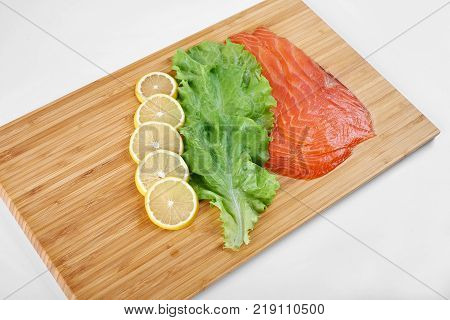 Smoked Fillet salmon with lemon and salad on a board