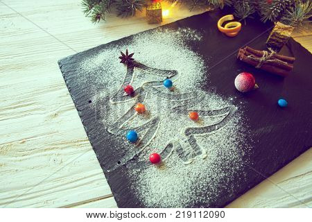 Christmas tree made from flour on a black background with anise stars and cinnamon sticks. Merry Christmas.