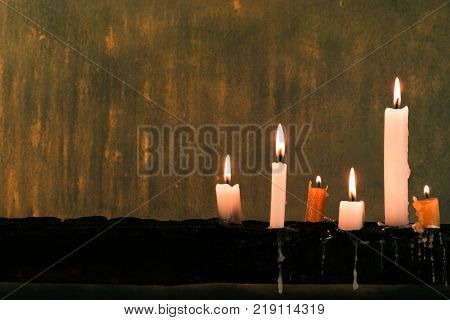 Candles on an old wooden burnt table. Beautiful dark background. Religious concept.