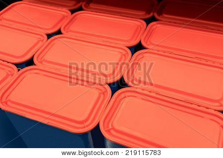 Rows of red plastic lids with blue containers for background.