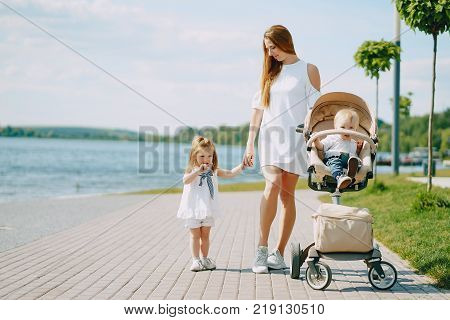 a beautiful young long-haired mom in the park with her beautiful little son and charming daughter