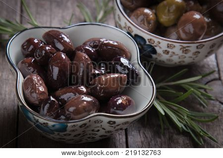 Cured, pickled or brined olive fruit on wooden table