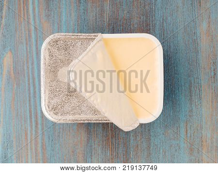 new full pack with melted cheese on lihgt blue wooden table, foil covering half of the product