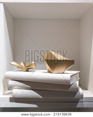 Gold Abstract Paperweight Placing On A Stack Of White Cover Books