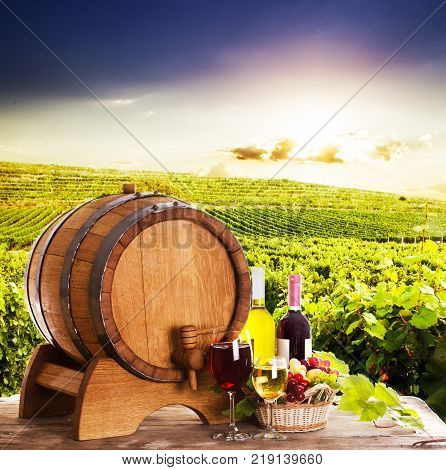 Grapes and bottels of wine near the wooden barrel. Glasses of wine on the table, concept of winery - red and white