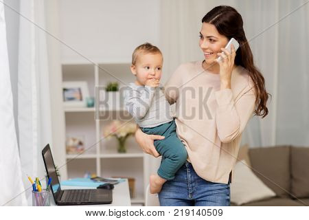 motherhood, multi-tasking, family and people concept - happy mother with baby calling on smartphone at home
