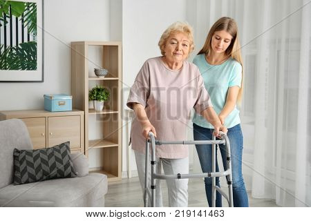 Young woman and her elderly grandmother with walking frame at home