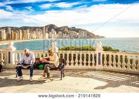 BENIDORM, SPAIN, DECEMBER 14, 2017: Eldery couple relax sitting on the bench in Mediterranean Balcony in Benidorm, Spain