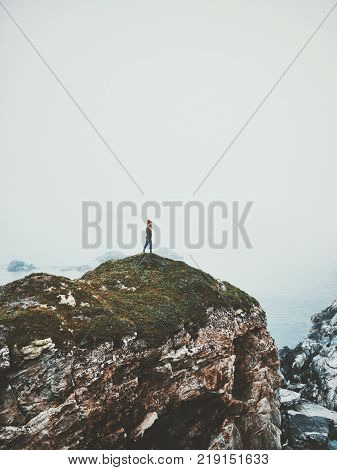 Traveler alone on seaside rocky cliff Norway islands Travel Lifestyle adventure concept vacations outdoor foggy landscape