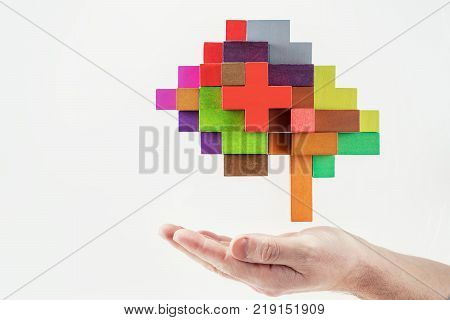 Human hand holding abstract brain. Human brain is made of multi-colored wooden blocks.