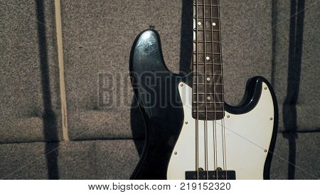Bass guitar stand beside microphone tripod and absorb wall in the sound studio production.