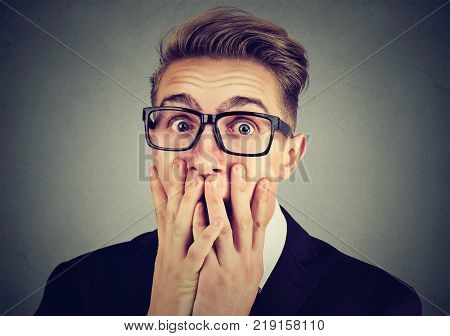 Portrait of a young anxious man looking shocked scared looking at camera