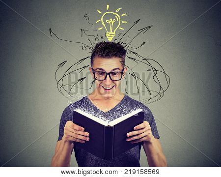 Happy man reading a book with light bulb above head